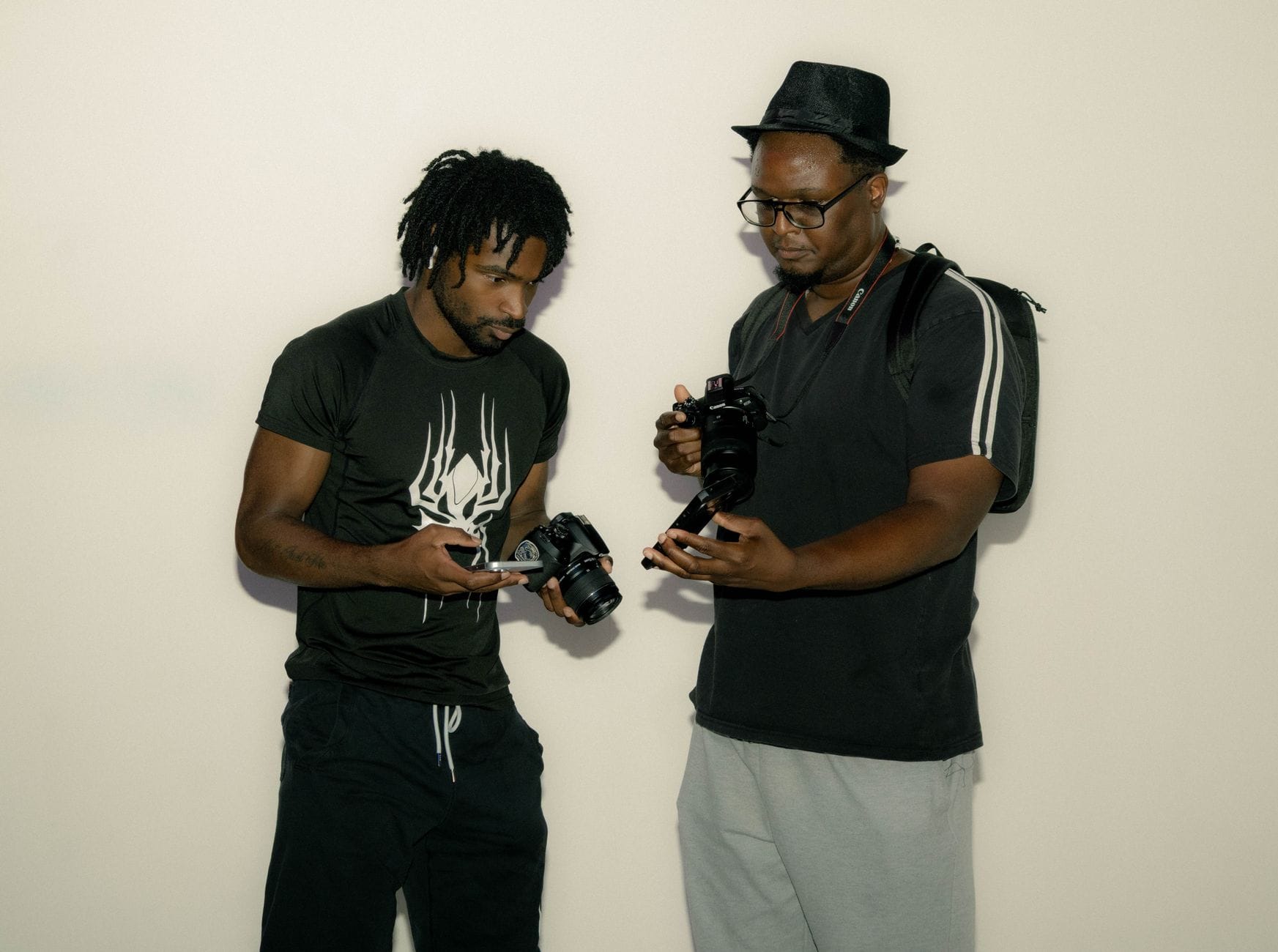 Two photographers indoors discussing and examining cameras passionately, fostering collaboration and learning.